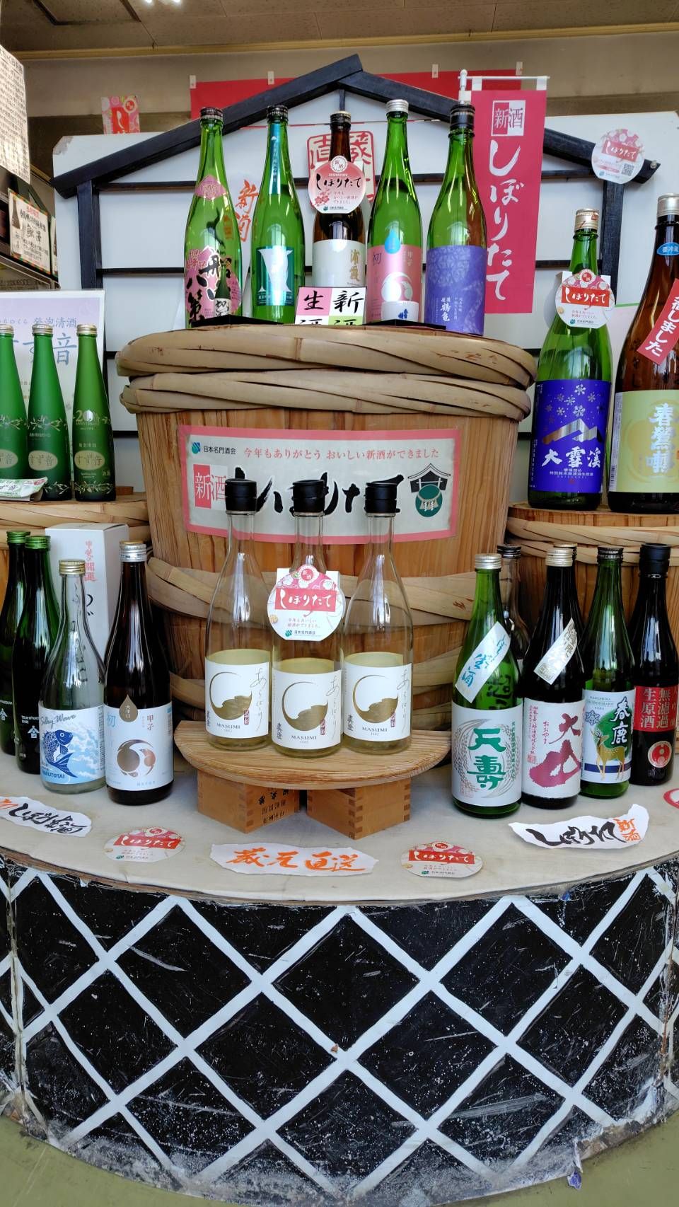 新酒しぼりたての店頭ディスプレイ。酒樽の上に新酒の瓶が並ぶ